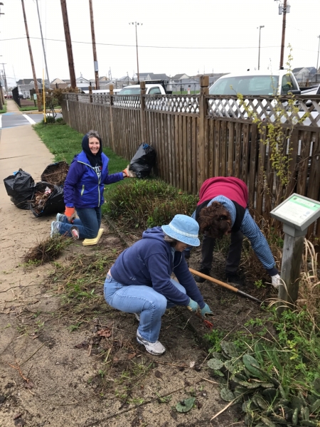 Three women are tending to a garden in a yard